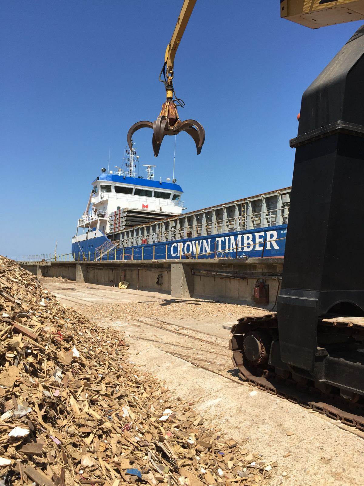 Waste wood on the quay beside a cargo ship