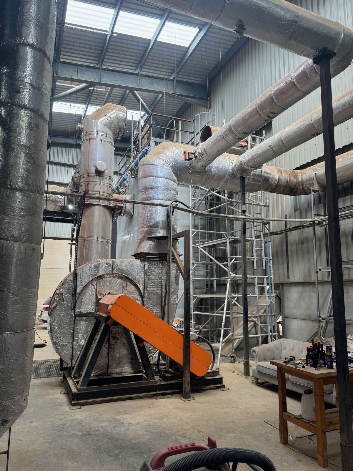 Waste-to-energy plant hall with fan, flue and pipework
